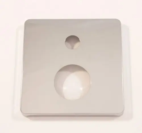 Quadratische Rosette aus Chrom von Ideal Standard mit zwei Öffnungen, einer runden und einer kleineren, auf glatter Oberfläche.